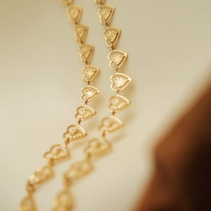 Macro shot of gold heart-shaped chain links with sunburst texture details