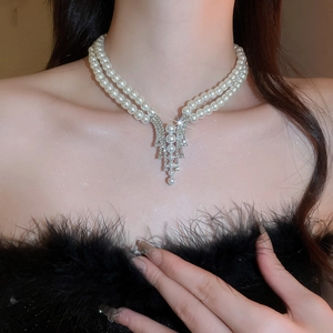 Detail of elegant double-layer pearl necklace with a shimmering V-shaped pendant on neck