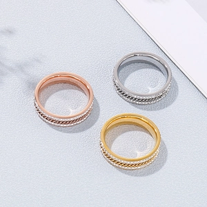 Three-color titanium steel rings with pavé diamonds and woven texture on stone surface