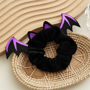 Macro detail of black plush Halloween bat scrunchie with purple glitter wings in a basket