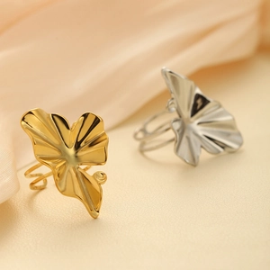 Detailed view of gold and silver leaf-shaped open rings on a textured surface