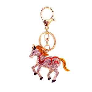 Golden running horse keychain with sparkling pink rhinestones on a white background