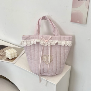 Dettaglio della borsa a righe rosa con applicazione in pizzo a cuore e fiocco decorativo