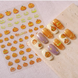 Macro detail of pumpkin Halloween nail stickers with gold and orange embossed patterns