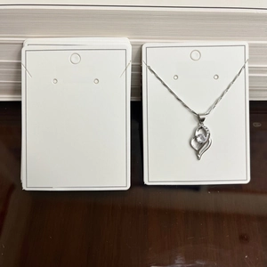 Silver heart necklace with clear zircon pendant displayed on white jewelry cards