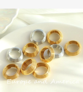 Macro shot of 18K gold and silver layered coil rings with textured striped design