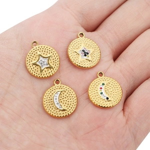 Gold stainless steel star and moon round pendants with rhinestones held in a hand