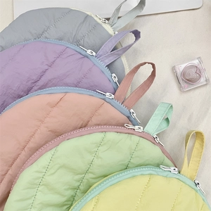 Detailed stack of multi-color quilted cosmetic bags in soft macaron pastel tones