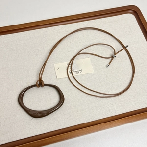 Detail of adjustable brown cord necklace with irregular geometric pendant on linen tray