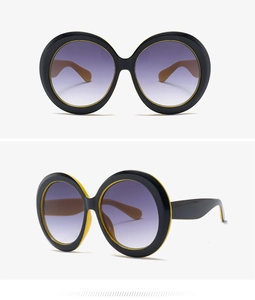 Detail view of round oversized sunglasses with black yellow frame and purple gradient lenses