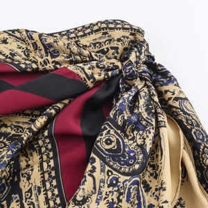 Macro detail of silky satin paisley fabric with intricate gold and wine red patterns