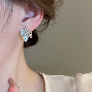 Detail of blue enamel leaf earrings with sparkling zircon accents on model