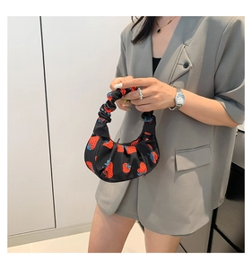 Dettaglio della borsa a tracolla plissettata nera con stampe di fragole e texture morbida