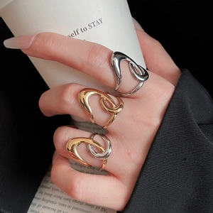 Close-up of three starfish geometric open rings in gold and silver on a hand