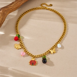 Gold stainless steel Cuban chain necklace with ladybug and bee charms on sand background