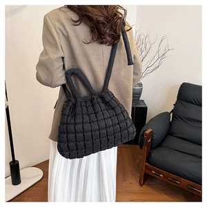 Quilted black tote bag shown on a model in a modern living room setting