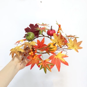 Detail of autumn candle ring with maple leaves, mini pumpkins, and orange berries