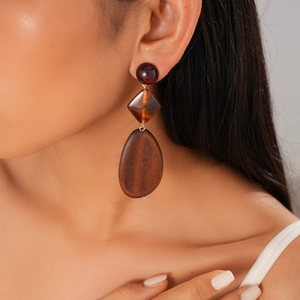 Close-up of bohemian brown resin and wood pendant earrings worn by a model