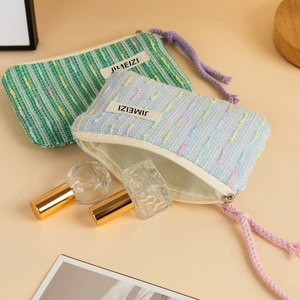 Detailed view of woven fabric makeup bags in light green and blue with purple pull strings