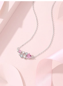 Macro shot of S925 silver heart necklace with pink gems and star pendant detail