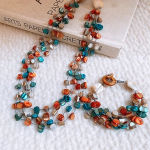 Close-up of layered shell bead necklace and bracelet with colorful stones and T-bar clasp