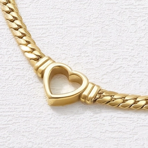 Detailed close-up of a chunky golden heart pendant on a bold flat chain necklace