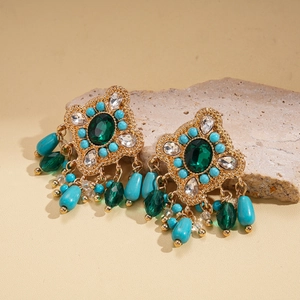 Detailed close-up of bohemian rhinestone earrings with green crystals and teardrop beads
