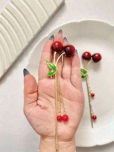 Detail of metal cherry hair stick with ruby-red fruit and gold tassel fringe