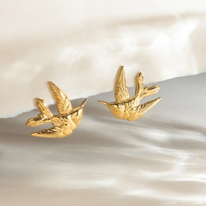 Vue macro de boucles d'oreilles hirondelle dorées avec textures de plumes détaillées