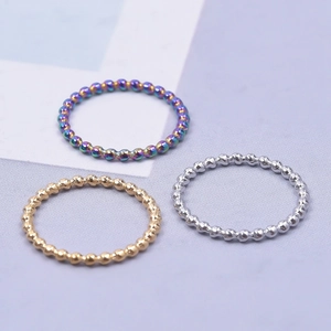 Three beaded stainless steel rings in rainbow gold and silver on a clean background