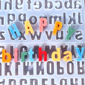 Silicone alphabet mold with colorful Happy Birthday candles on wood background