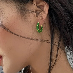Elegante C-förmige grüne Emaille-Ohrringe mit vergoldeter Spiralstruktur getragen von Modell