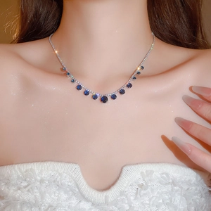 Close-up of sparkling silver necklace with round blue stones and clear crystals on a model