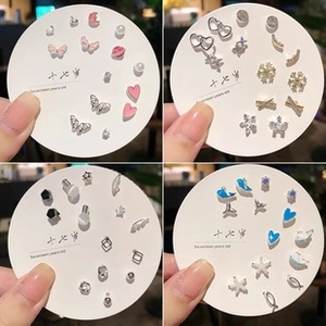 Close-up of mixed earring set with butterfly and heart studs on a white display card