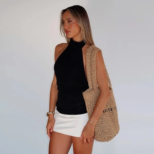 Detail shot of black halter neck knitted top paired with a white mini skirt on a model