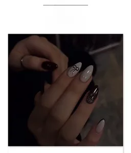 Macro view of Y2K style almond press-on nails featuring black bows and French tips