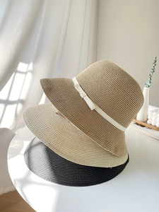 Detail of woven straw hats with white ribbon bows in khaki, cream, and black colors