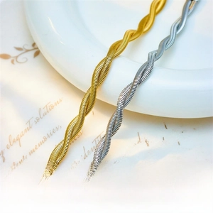 Detail of twisted flat snake chain bracelets in polished gold and silver finishes