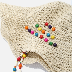 Détail du chapeau de paille au crochet avec perles en bois colorées et texture