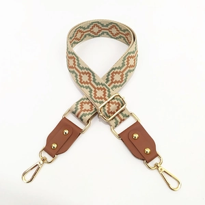 Detail of adjustable woven purse strap with beige jacquard pattern and brown leather ends