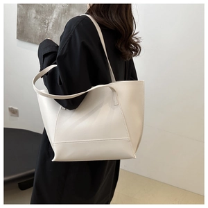 Detail of a large cream tote bag showing smooth leather texture and long shoulder strap