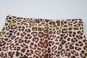Détail du tissu imprimé léopard avec coutures contrastées vert fluo sur haut ajusté
