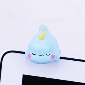 Detailed view of a cute blue resin dinosaur ornament resting on a white monitor screen