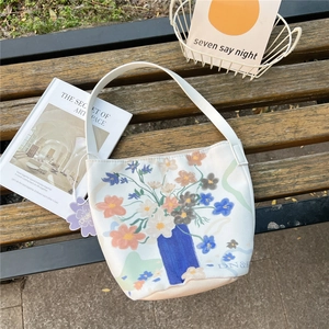Detailed close-up of a floral canvas bucket bag on a park bench with lifestyle props