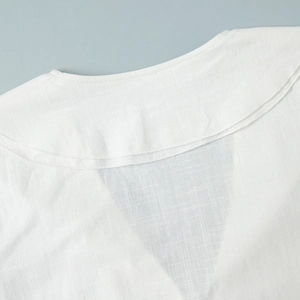 Close-up of white cotton shirt neckline with refined stitching and textured fabric details