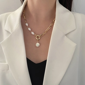 Vintage baroque pearl pendant gold chain necklace shown on a model in white blazer