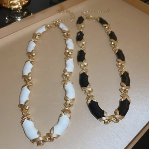 Détails des colliers vintage en émail noir et blanc avec des maillons croisés dorés