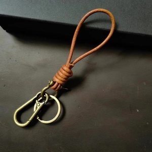 Detail of hand-woven brown leather cord keychain with vintage brass horseshoe buckle