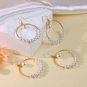 Golden circular pearl hoop earrings set with hooks and clip-ons on white silk and marble