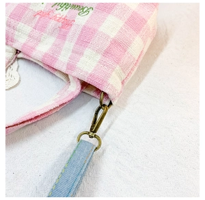 Detail of pink plaid canvas kid's bag with bronze ring and blue strap attachment